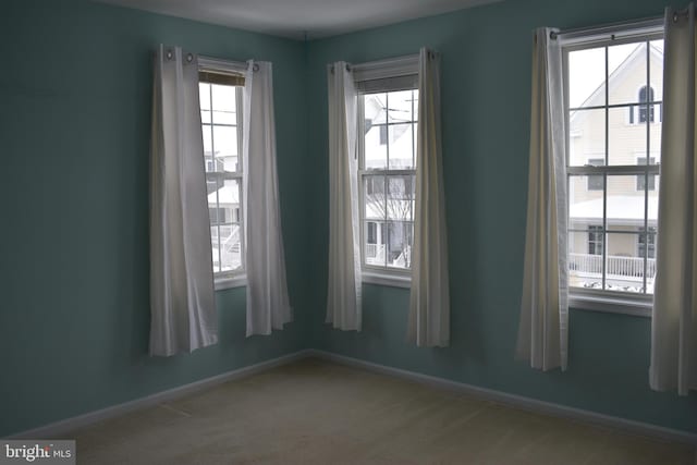 unfurnished room featuring carpet flooring and plenty of natural light