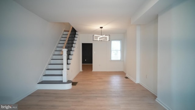 foyer entrance with light hardwood / wood-style floors, an AC wall unit, and a chandelier