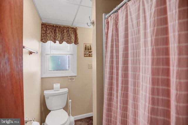 bathroom with a paneled ceiling, toilet, and walk in shower