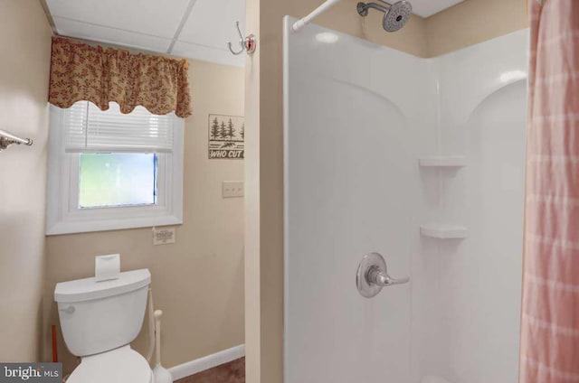 bathroom featuring a shower, a drop ceiling, and toilet