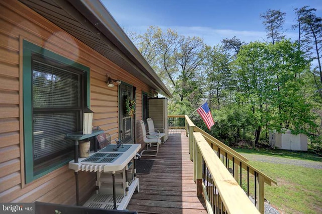 wooden terrace featuring a lawn and a storage unit