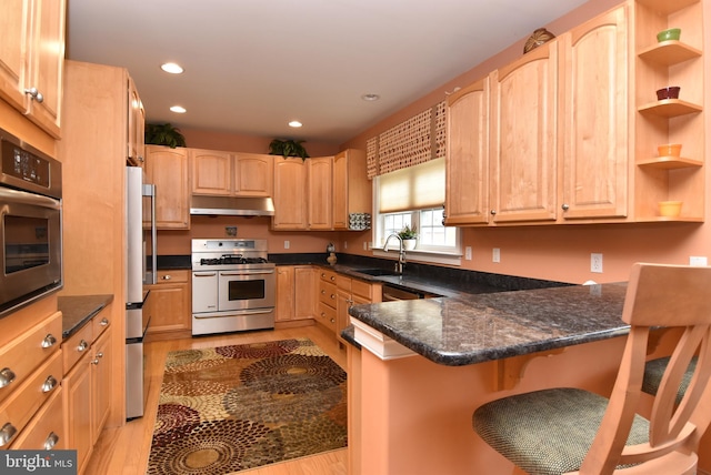 kitchen with kitchen peninsula, stainless steel appliances, sink, light hardwood / wood-style floors, and a breakfast bar area