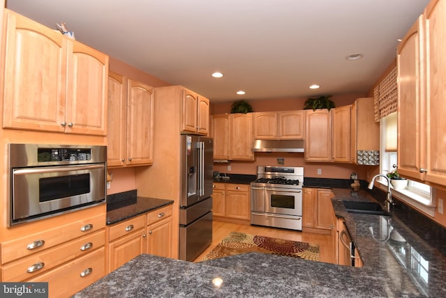 kitchen featuring sink, light brown cabinets, stainless steel appliances, dark stone countertops, and light wood-type flooring