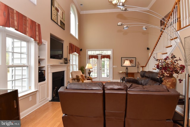 living room featuring plenty of natural light, light hardwood / wood-style floors, a towering ceiling, and crown molding