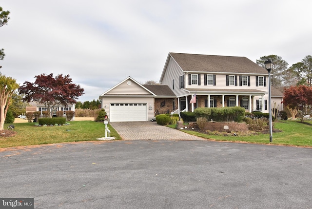 view of front of property with a front lawn, covered porch, and a garage