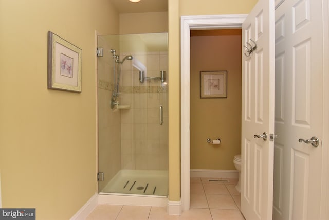 bathroom featuring tile patterned flooring, toilet, and a shower with door