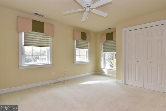 unfurnished bedroom with light carpet, a closet, and ceiling fan