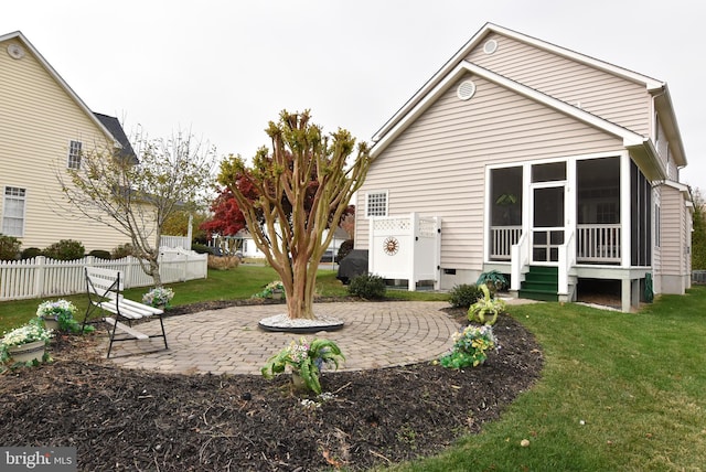 rear view of house with a lawn, a sunroom, and a patio area