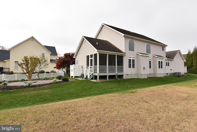 rear view of house featuring a sunroom and a lawn