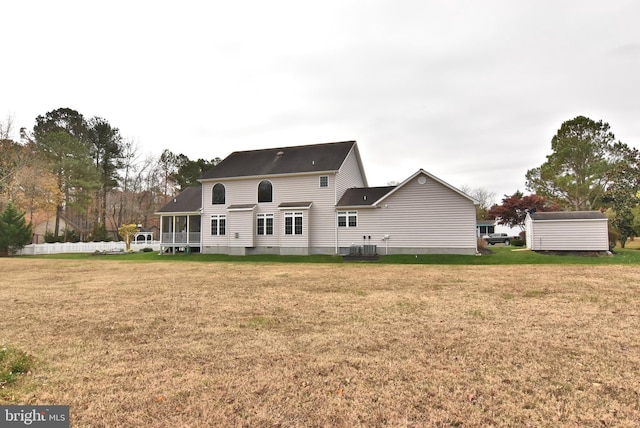 rear view of house featuring a lawn, a sunroom, and central air condition unit