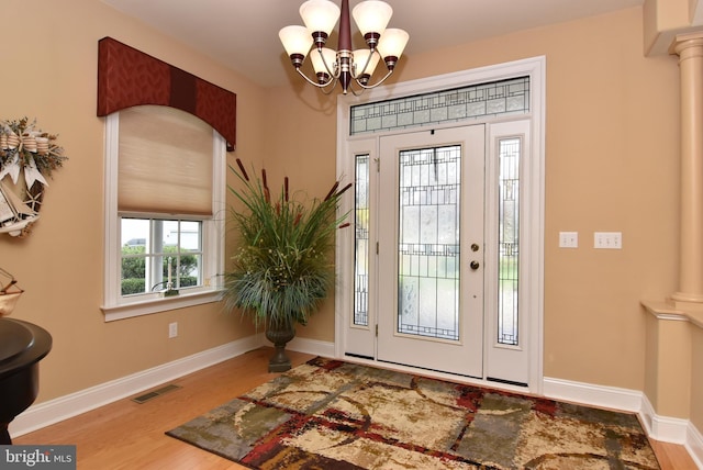 entryway with hardwood / wood-style flooring, an inviting chandelier, and ornate columns