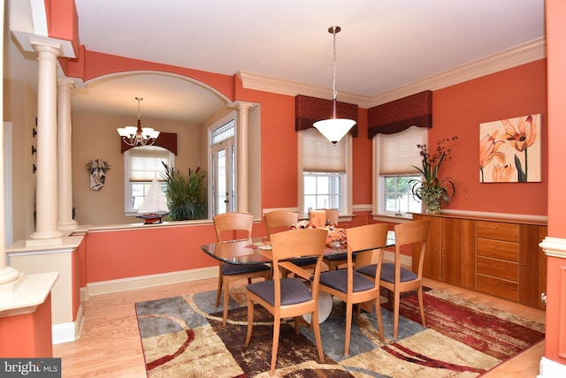 dining room with light hardwood / wood-style floors, ornamental molding, and an inviting chandelier