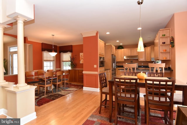 dining room featuring decorative columns, light hardwood / wood-style flooring, and crown molding