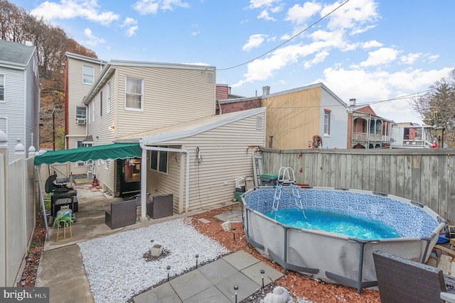 rear view of house featuring a patio area and a fenced in pool