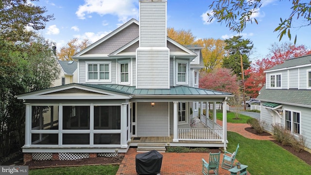 rear view of house with a sunroom, a yard, and a porch