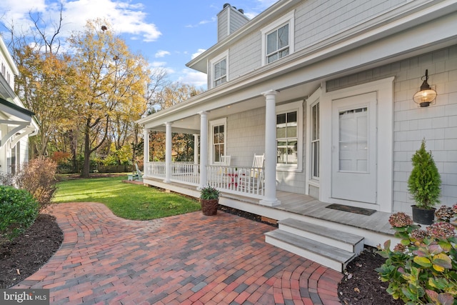 doorway to property featuring a lawn and a porch