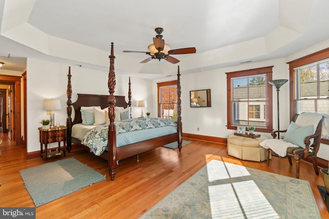 bedroom with hardwood / wood-style flooring, ceiling fan, and a raised ceiling