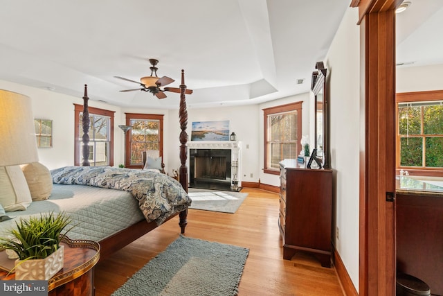 bedroom with a tray ceiling, light hardwood / wood-style flooring, and ceiling fan