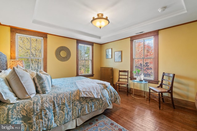 bedroom featuring hardwood / wood-style flooring, radiator heating unit, and a tray ceiling