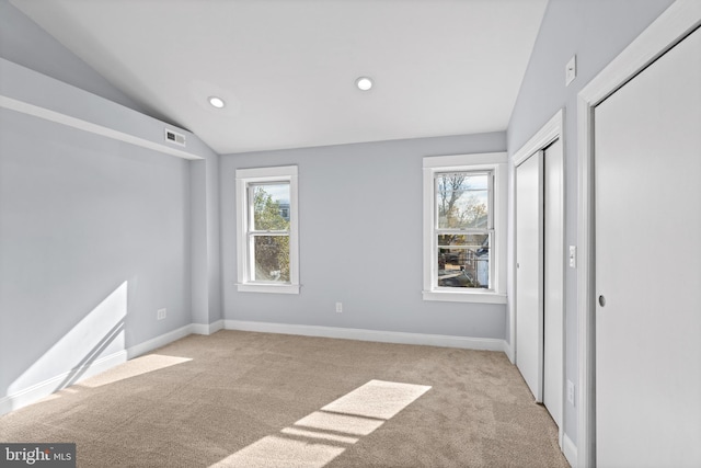 unfurnished bedroom with light carpet, vaulted ceiling, and multiple windows