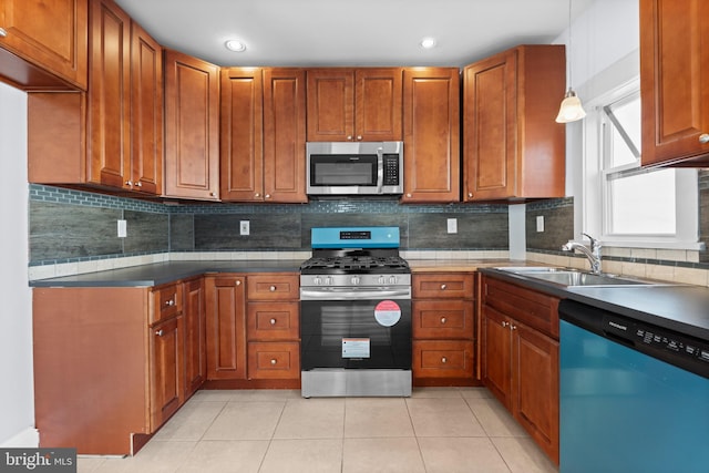 kitchen with pendant lighting, sink, decorative backsplash, light tile patterned floors, and stainless steel appliances