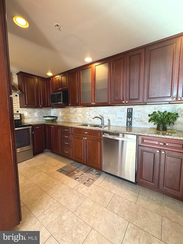 kitchen featuring appliances with stainless steel finishes, tasteful backsplash, light stone counters, sink, and light tile patterned flooring