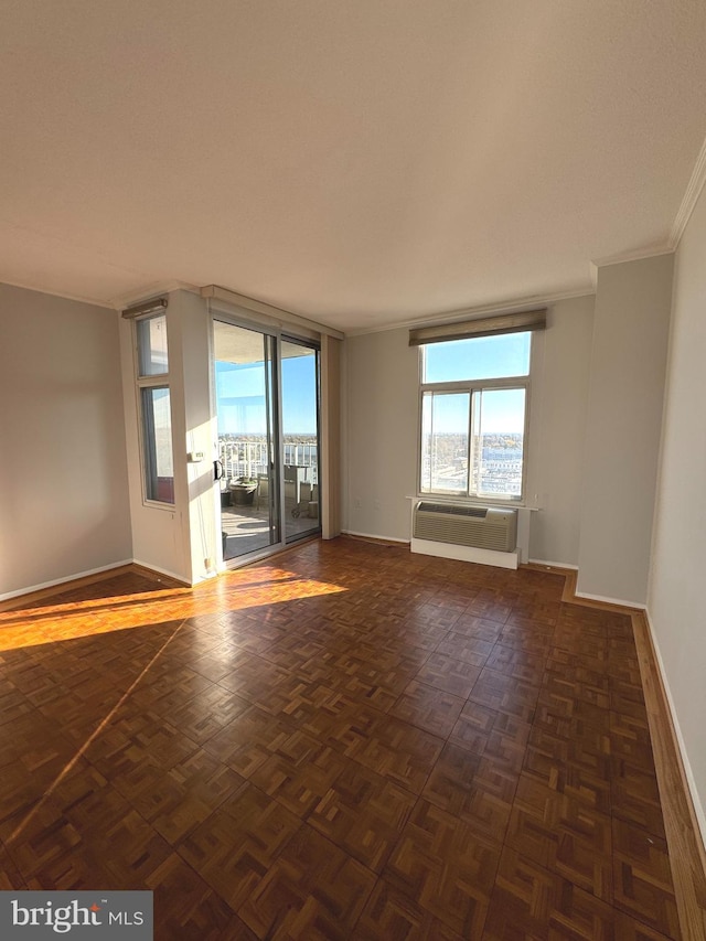 spare room with a wealth of natural light, dark parquet floors, a wall mounted air conditioner, and ornamental molding