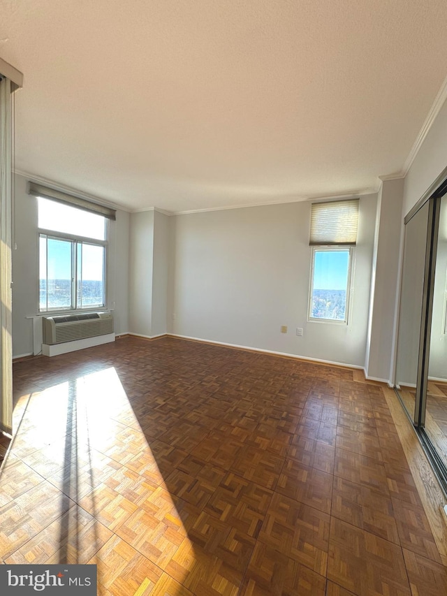 unfurnished room with a wall unit AC, dark parquet floors, and ornamental molding