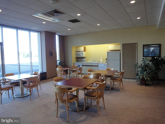 carpeted dining area with a paneled ceiling, a water view, and sink