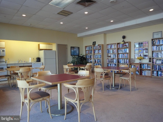 carpeted dining room with a paneled ceiling