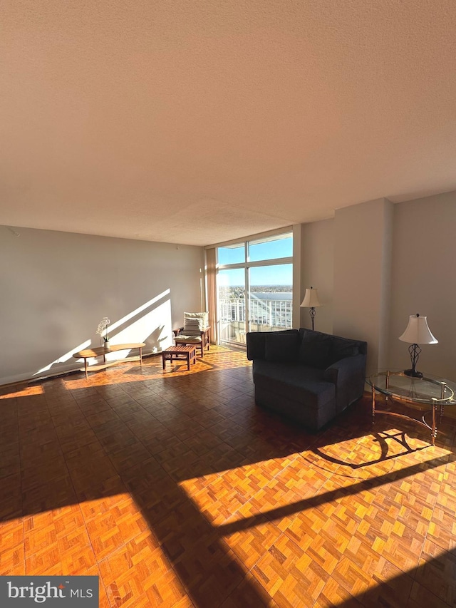 unfurnished living room featuring expansive windows, parquet floors, and a textured ceiling