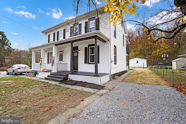 view of front of home featuring covered porch and a shed