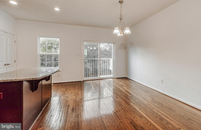 unfurnished dining area with dark wood-type flooring and a chandelier