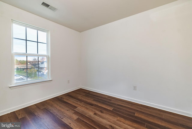 spare room with a wealth of natural light and dark hardwood / wood-style floors