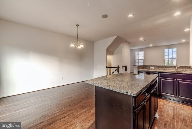 kitchen with pendant lighting, a center island, sink, dark wood-type flooring, and dark brown cabinets