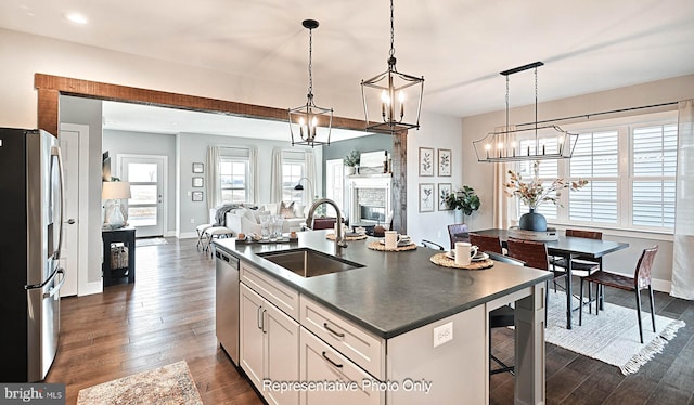 kitchen featuring appliances with stainless steel finishes, dark hardwood / wood-style flooring, a center island with sink, and pendant lighting