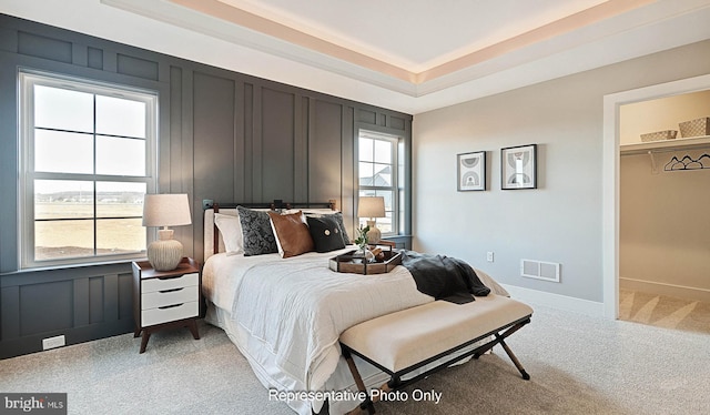 bedroom featuring carpet flooring, multiple windows, a walk in closet, and a closet