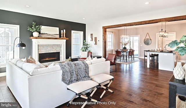 living room with a fireplace, an inviting chandelier, and dark wood-type flooring