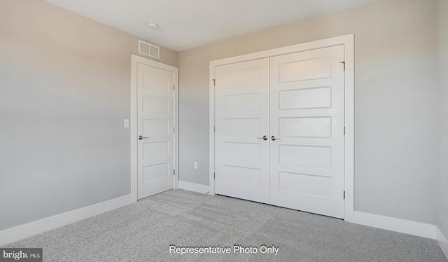 unfurnished bedroom with a closet and light colored carpet