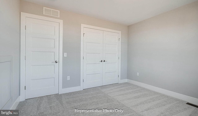 unfurnished bedroom featuring a closet and light colored carpet