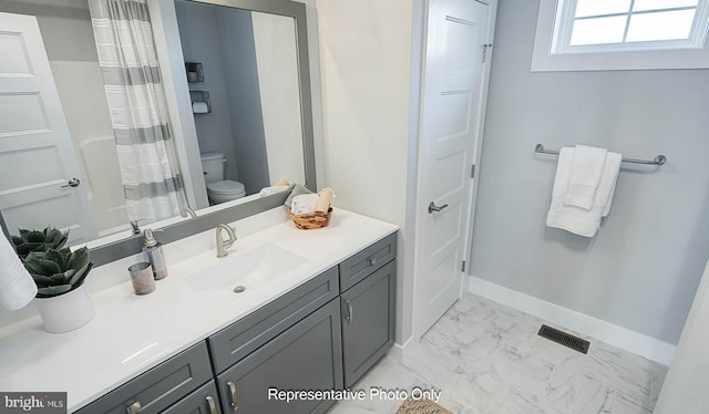 bathroom featuring walk in shower, vanity, and toilet