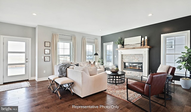 living room with dark hardwood / wood-style flooring and a stone fireplace