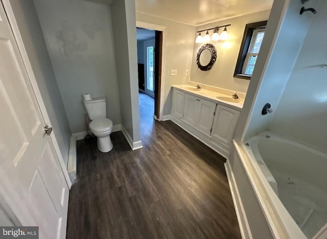 bathroom featuring a washtub, vanity, wood-type flooring, and toilet