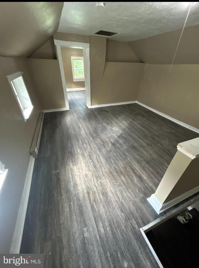 bonus room with a textured ceiling, dark hardwood / wood-style flooring, a baseboard radiator, and lofted ceiling