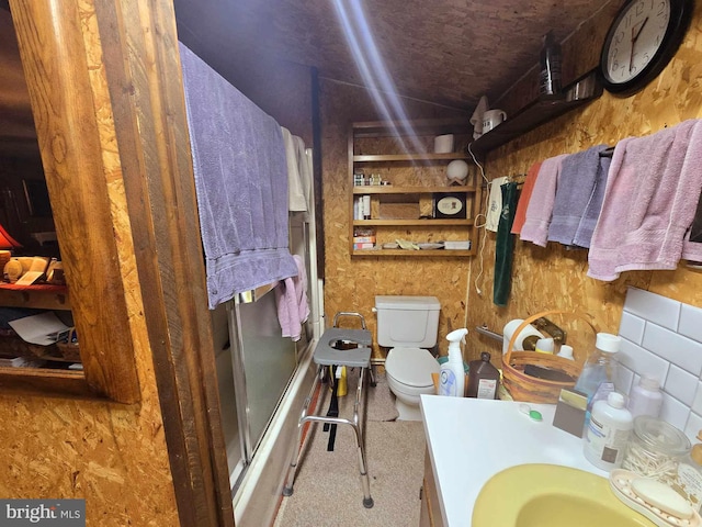 full bathroom with bath / shower combo with glass door, toilet, and sink