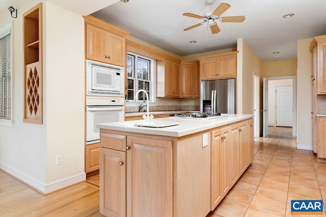 kitchen with light brown cabinets, a center island with sink, ceiling fan, light tile patterned flooring, and stainless steel appliances