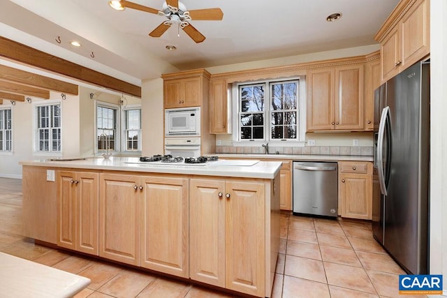 kitchen featuring light brown cabinetry, ceiling fan, a center island, and stainless steel appliances