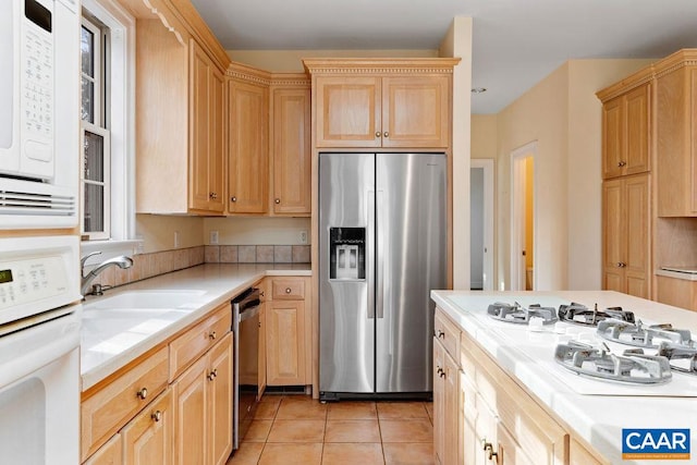 kitchen with light tile patterned floors, light brown cabinets, stainless steel appliances, and sink