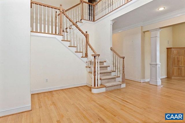 staircase with wood-type flooring, ornamental molding, and a high ceiling