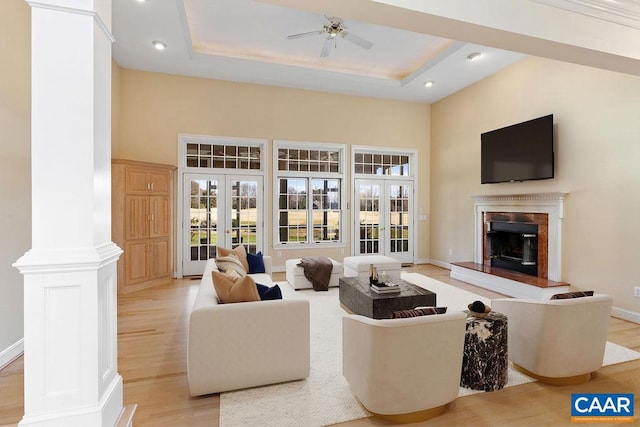 living room featuring a towering ceiling, light hardwood / wood-style floors, a raised ceiling, and ceiling fan